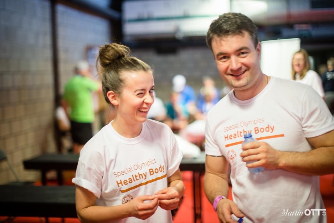 Zwei lachende Menschen in Healthy-Body-Shirts bei einer gemeinsamen Veranstaltung.